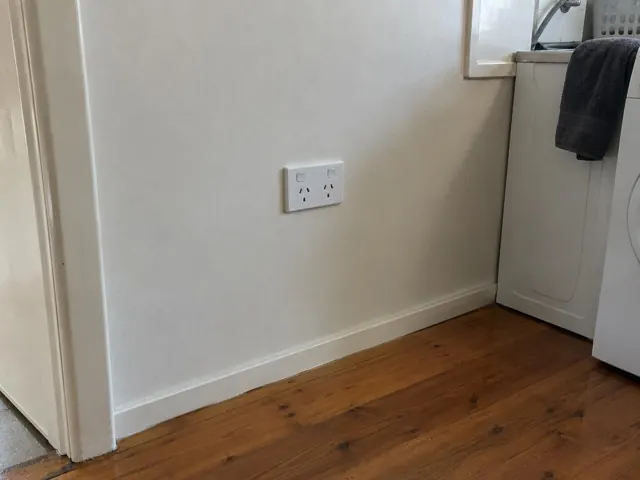White double power point on a painted laundry wall above timber flooring in Croudace Bay